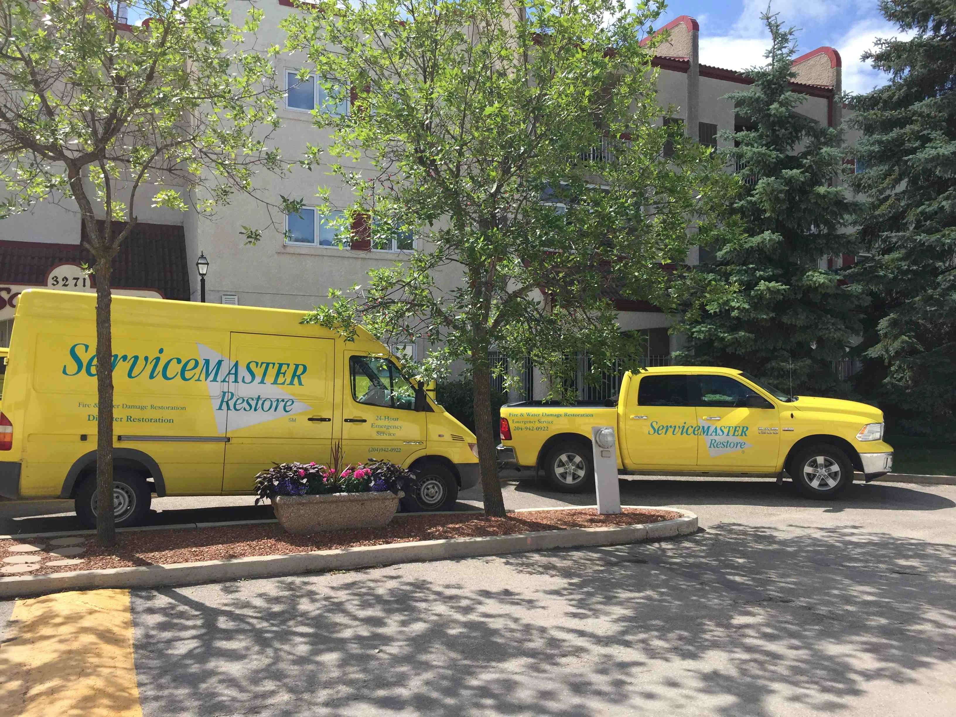 Two-yellow-ServiceMaster-vechicles-outside-apartment-building